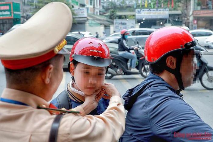 Cán bộ CSGT đeo mũ bảo hiểm cho cháu nhỏ để tiếp tục di chuyển đến trường.